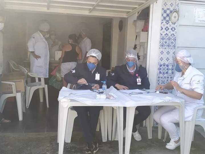 Profissionais de saúde em mesa de atendimento na campanha de vacinação